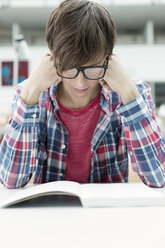 Student in a university library reading book - WESTF019542