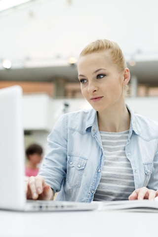 Student in einer Universitätsbibliothek mit Laptop, lizenzfreies Stockfoto