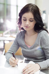 Student in a university library taking notes - WESTF019647