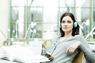 Student with headphones in a university library - WESTF019599