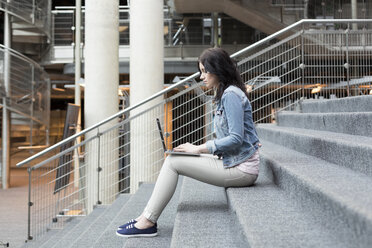 Junge Frau benutzt Laptop auf einer Treppe - WESTF019622