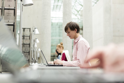 Studenten in einer Universitätsbibliothek mit Laptops, lizenzfreies Stockfoto