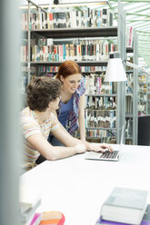 Zwei Studenten in einer Universitätsbibliothek mit Laptop - WESTF019715