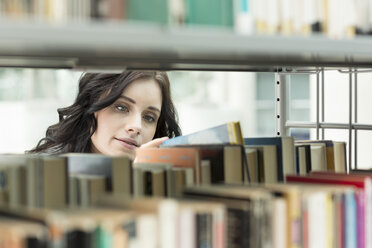 Student in einer Universitätsbibliothek, der ein Buch aus dem Regal nimmt - WESTF019722