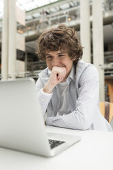 Student using laptop in a university library - WESTF019756