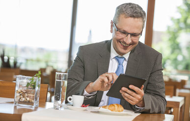 Geschäftsmann im Restaurant mit digitalem Tablet - DISF000844