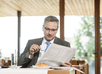 Businesman reading newspaper in restaurant - DISF000852