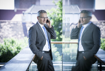 Businessman on cell phone on balcony - DISF000860