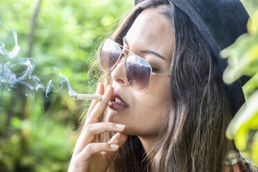 Portrait of smoking young woman with hat and sunglasses - DRF000704