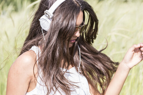 Porträt einer jungen Frau mit Kopfhörern auf einem Feld - DRF000702