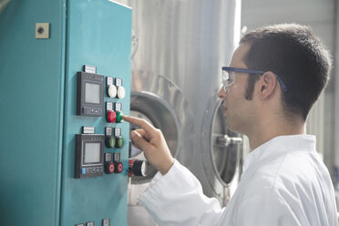 Chemiker in einem technischen Raum, der einen Knopf drückt - SGF000807