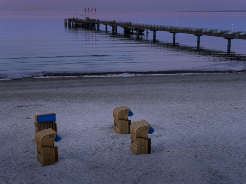 Deutschland, Schleswig-Holstein, Scharbeutz, Seebrücke und überdachte Strandkörbe am Strand, lizenzfreies Stockfoto