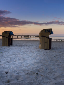 Deutschland, Schleswig-Holstein, Scharbeutz, Seebrücke, Überdachte Strandkörbe am Strand am Abend - AMF002464