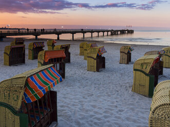 Deutschland, Schleswig-Holstein, Scharbeutz, Seebrücke, Überdachte Strandkörbe am Strand am Abend - AMF002465