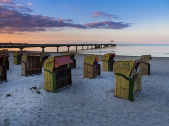 Deutschland, Schleswig-Holstein, Scharbeutz, Seebrücke, Überdachte Strandkörbe am Strand am Abend - AMF002467