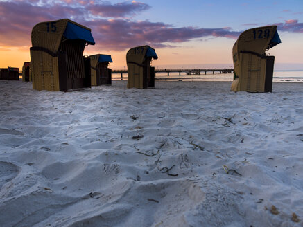 Deutschland, Schleswig-Holstein, Scharbeutz, Seebrücke, Überdachte Strandkörbe am Strand am Abend - AMF002469