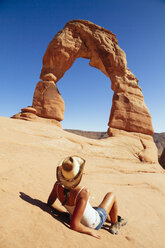 USA, Utah, Frau entspannt sich vor dem Delicate Arch im Arches National Park, Rückansicht - MBEF001049