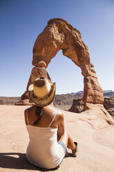 USA, Utah, Frau vor dem Delicate Arch im Arches National Park sitzend, Rückansicht - MBEF001050