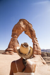 USA, Utah, Woman looking at Delicate Arch in Arches National Park, back view - MBEF001051