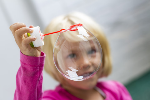 Porträt eines kleinen Mädchens, das Seifenblasen macht, lizenzfreies Stockfoto