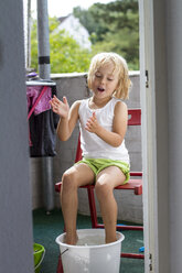 Porträt eines kleinen Mädchens beim Fußbad auf dem Balkon - JFEF000436