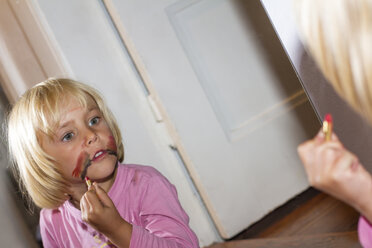 Little girl painting her face in front of mirror - JFEF000447