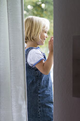 Portrait of little girl standing at the window - JFEF000450