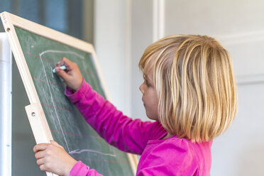 Kleines Mädchen malt mit Buntstiften auf einer Wandtafel - JFEF000455