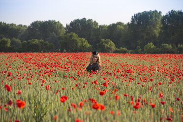 Woman wearing black cap standing in poppy field - YFF000189