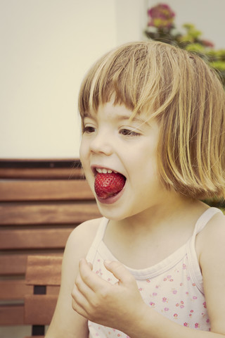 Portrait of little girl with strawberry in her mouth stock photo