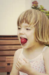 Portrait of little girl with strawberry in her mouth - LVF001485