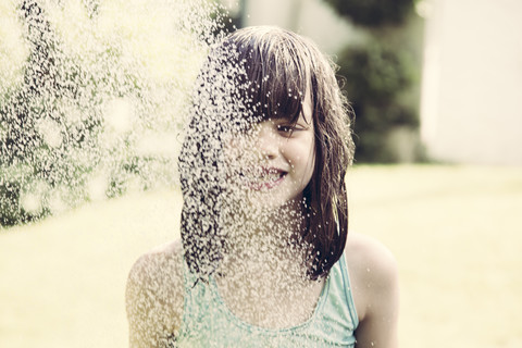 Porträt eines kleinen Mädchens beim Duschen im Garten, lizenzfreies Stockfoto