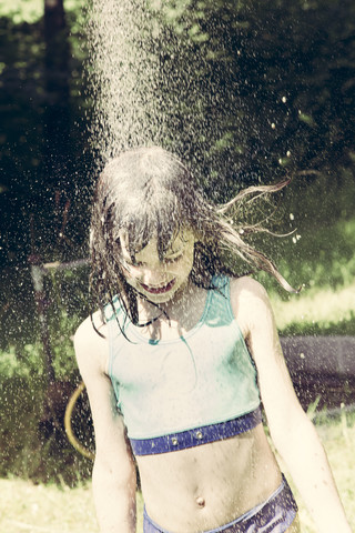Kleines Mädchen beim Duschen im Garten, lizenzfreies Stockfoto