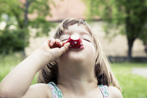 Portrait of little girl playing with doll's china set in the garden stock photo