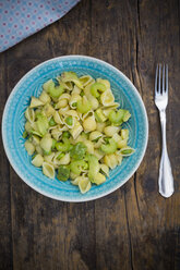 Plate of noodle salad with avocado, peas and celery on wood, elevated view - LV001483