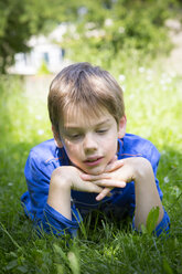 Porträt eines träumenden Jungen auf einer Wiese liegend - LVF001501