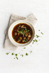 Soup plate of Japanese miso soup with carrots and mushrooms on cloth and white ground - EVG000651