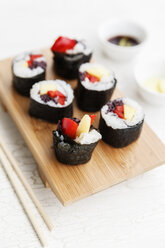 Futo Maki with mango and bell pepper on wooden board, dipping bowls and chop sticks - EVG000654