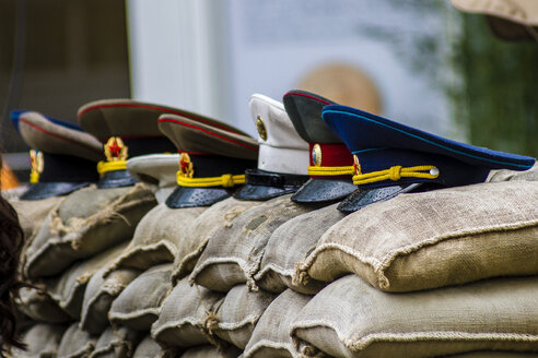 Germany, Berlin, view to row of uniform caps lying on sand bags at Checkpoint Charlie - BIG000010