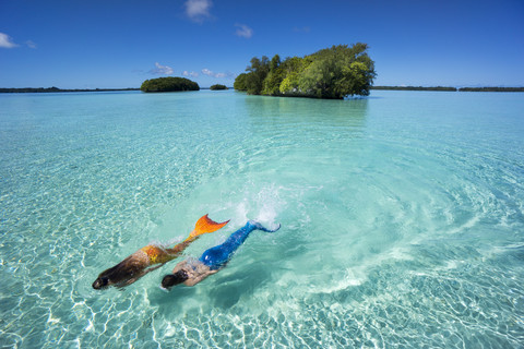 Palau, zwei junge Frauen im Meerjungfrauenkostüm schwimmen in einer Lagune, lizenzfreies Stockfoto