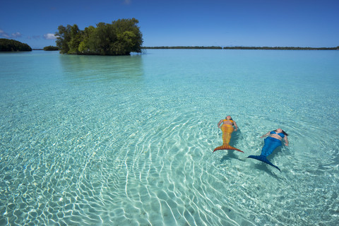 Palau, zwei junge Frauen im Meerjungfrauenkostüm schwimmen in einer Lagune, lizenzfreies Stockfoto