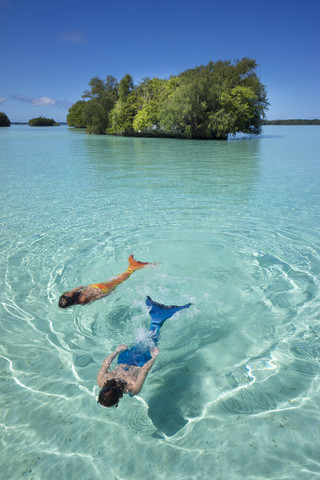 Palau, zwei junge Frauen im Meerjungfrauenkostüm schwimmen in einer Lagune, lizenzfreies Stockfoto