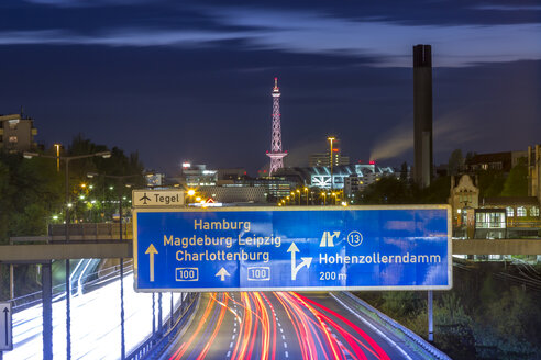 Deutschland, Berlin, Berlin-Charlottenburg, Bundesautobahn 100 durch das Zentrum von Berlin mit dem Funkturm Berlin und den Messehallen im Hintergrund bei Nacht - NKF000151