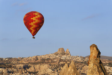 Turkey, Cappadocia, hot air balloon hoovering in front of the village Uchisar at Goereme National Park - SIEF005523