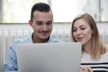Smiling man and woman using laptop - STKF000993
