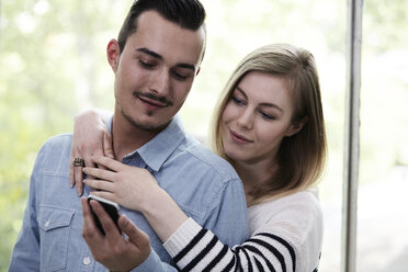 Couple with cell phone at a window - STKF000997