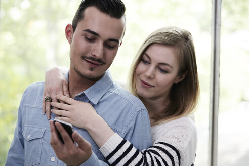 Pärchen mit Handy am Fenster - STKF000997