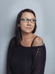 Porträt einer brünetten Frau mit Brille vor einem grauen Hintergrund - STKF000949
