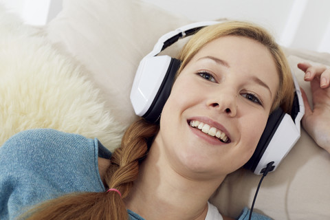 Porträt eines weiblichen Teenagers, der zu Hause mit Kopfhörern Musik hört, lizenzfreies Stockfoto