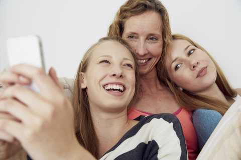 Porträt einer Mutter und ihrer beiden Töchter zu Hause, lizenzfreies Stockfoto